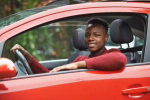 Teenager Sitting In Red Car Smiling